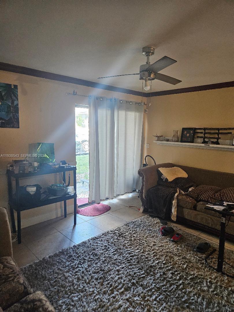 A living room features tile flooring, a ceiling fan, a sofa, and a sliding glass door — 18755 NW 62nd Ave # 101, Hialeah FL 33015, HIALEAH, FL