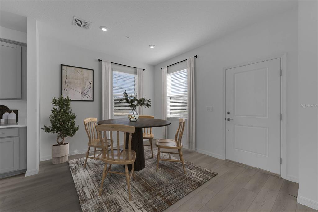 A dining area features a round wooden table, four chairs, a patterned rug, and windows — 33192 CONTENTMENT WAY, WESLEY CHAPEL, FL