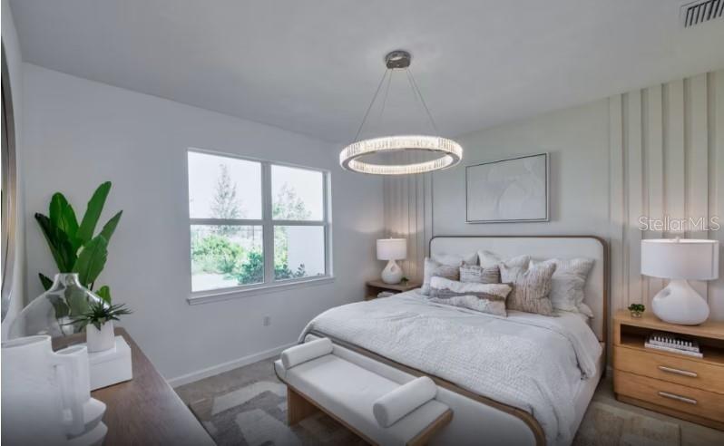 A modern bedroom features a circular chandelier, a white upholstered bed, and light wood nightstands — 1620 TAVIRA PLACE, ENGLEWOOD, FL