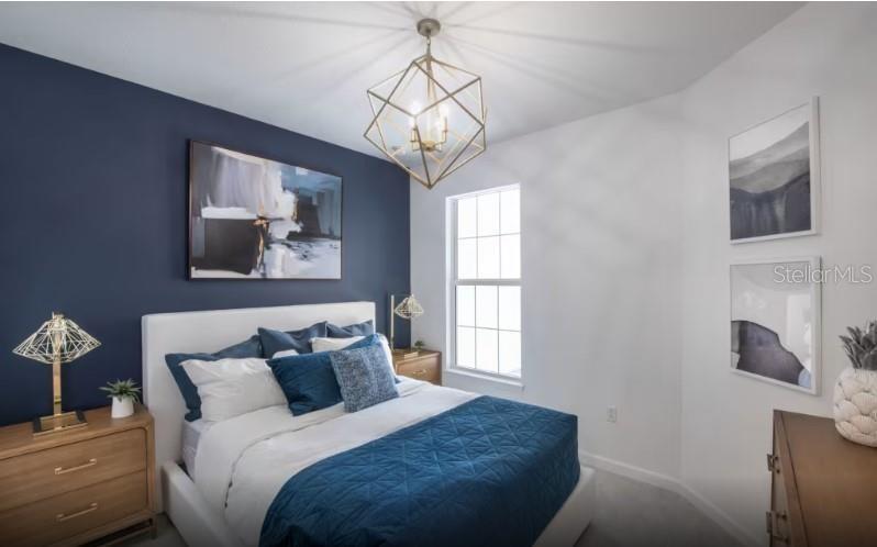 A bedroom features a navy accent wall, a geometric chandelier, and a white upholstered bed — 1620 TAVIRA PLACE, ENGLEWOOD, FL