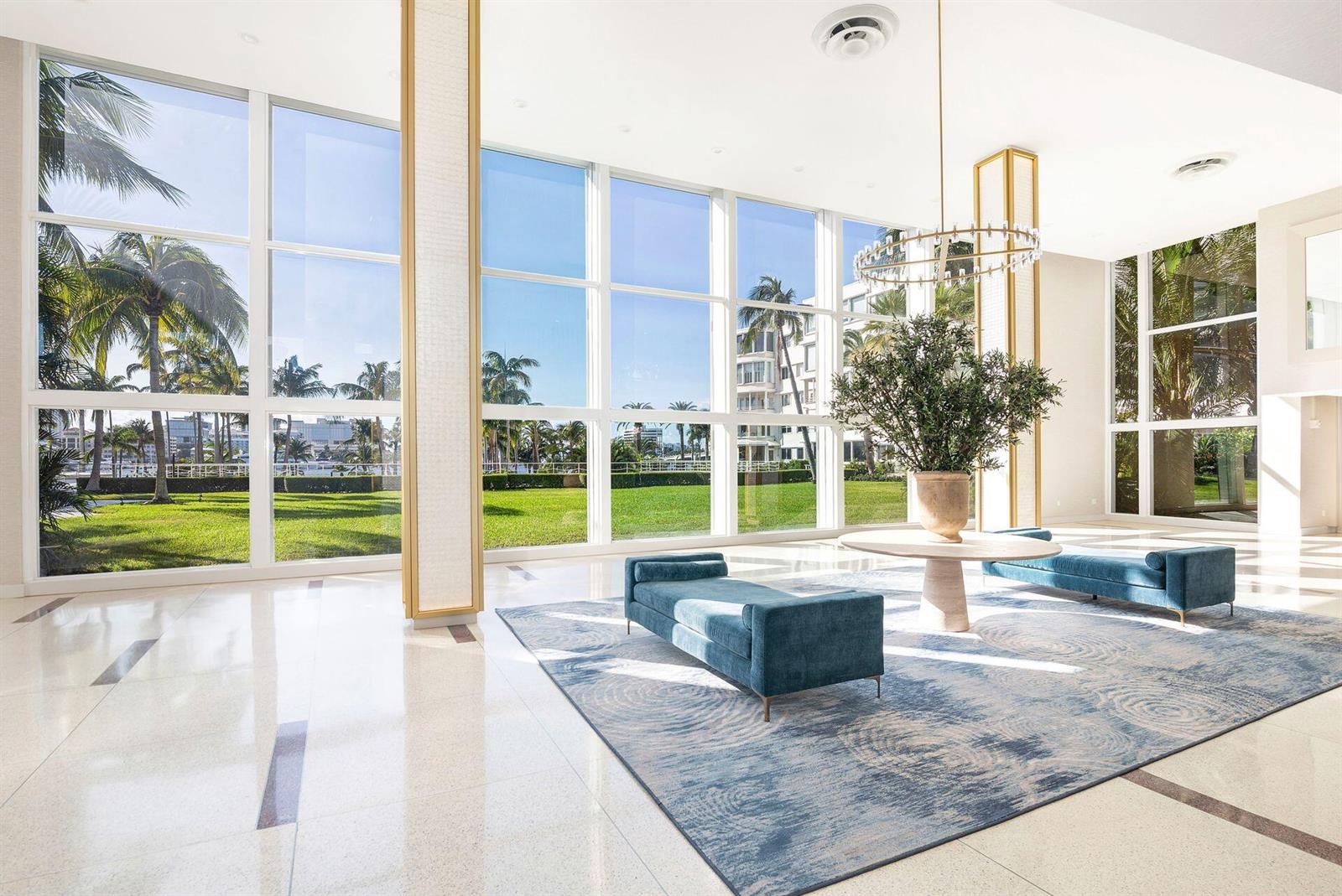 A bright lobby features floor-to-ceiling windows, blue velvet benches, and a large central plant — 44 Cocoanut Row # 227b, Palm Beach FL 33480, PALM BEACH, FL