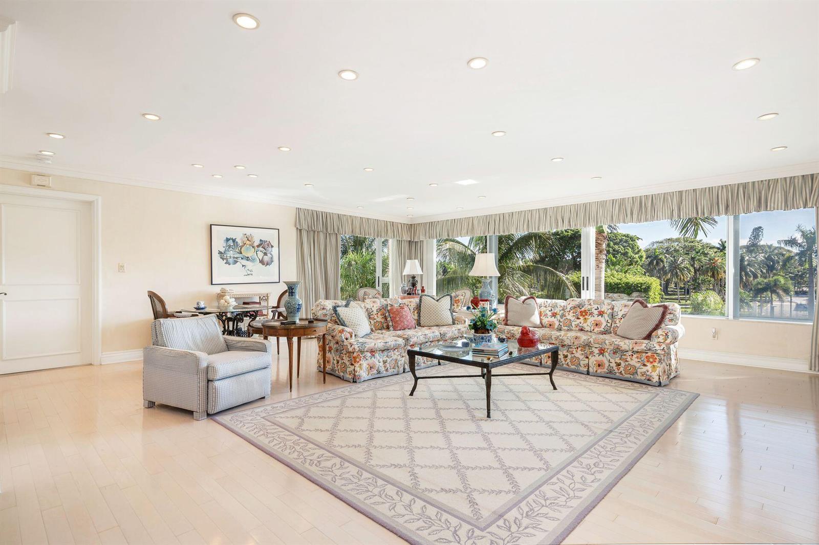 A spacious living room features floral sofas, a patterned rug, and large windows with garden views — 44 Cocoanut Row # 227b, Palm Beach FL 33480, PALM BEACH, FL