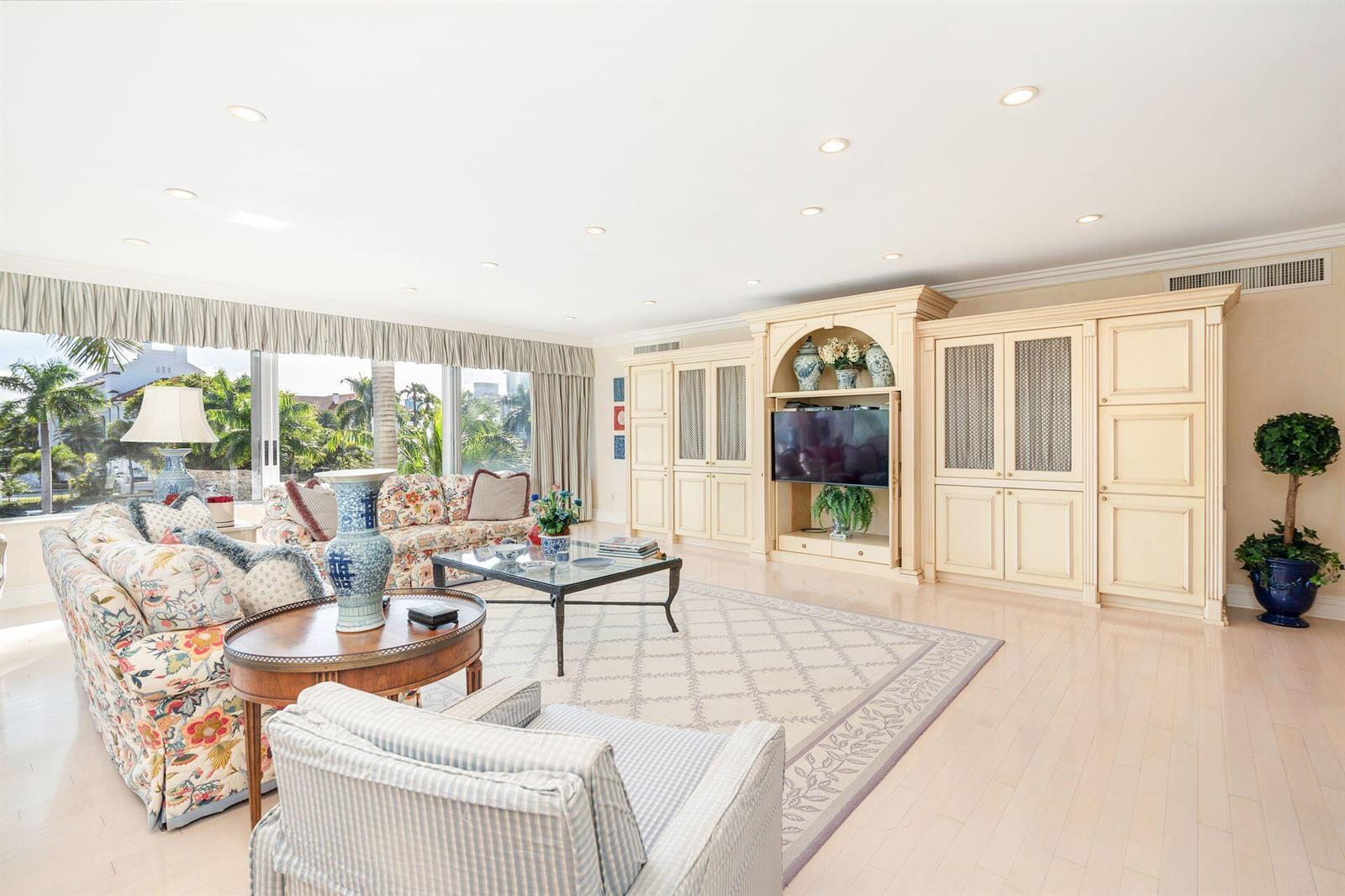 A living room features floral sofas, a large entertainment center, and floor-to-ceiling windows — 44 Cocoanut Row # 227b, Palm Beach FL 33480, PALM BEACH, FL