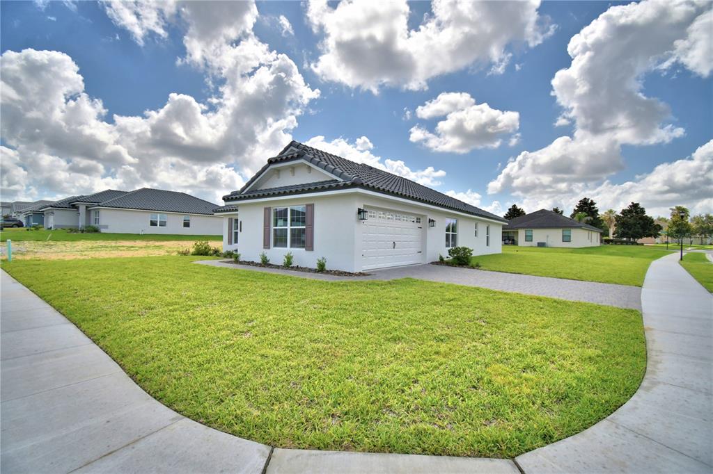A white single-story house with a tiled roof and a paved driveway sits on grass — 4502 GRANDVIEW GLEN DRIVE, AUBURNDALE, FL