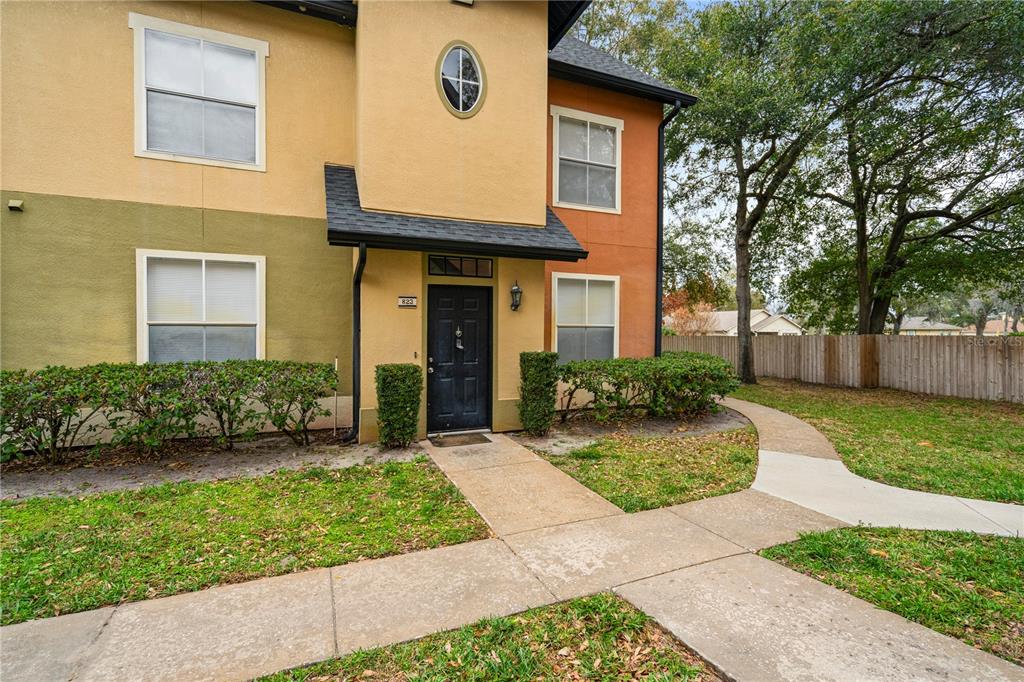 A two-story building exterior features tan and orange stucco walls with a black front door — 6021 WESTGATE DRIVE UNIT 823, ORLANDO, FL