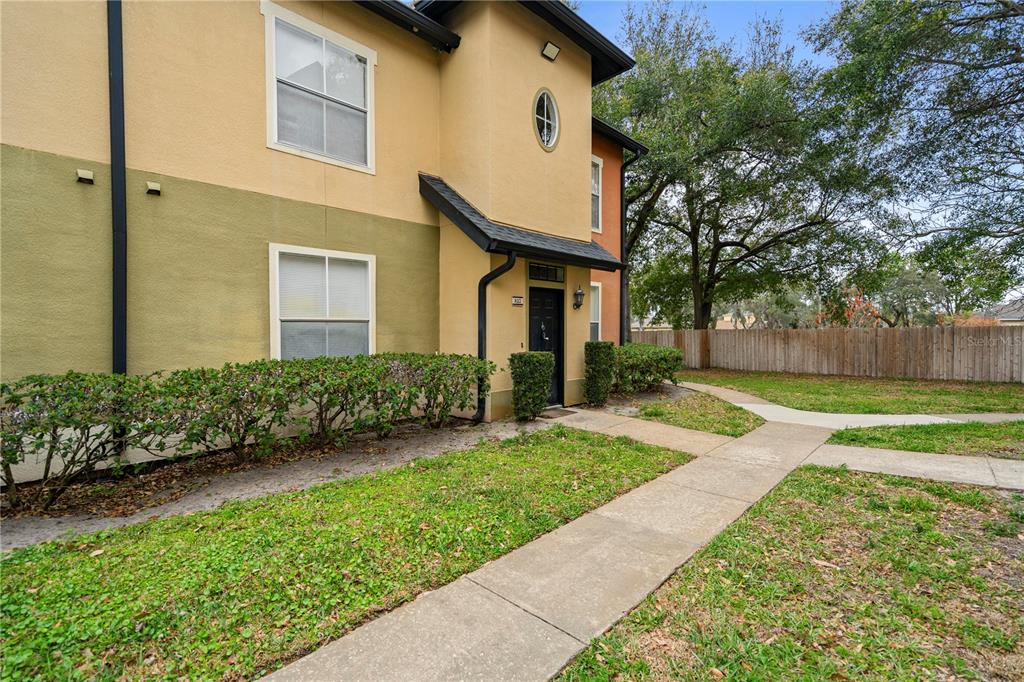 A two-story apartment building exterior features tan and green stucco walls with a black door — 6021 WESTGATE DRIVE UNIT 823, ORLANDO, FL