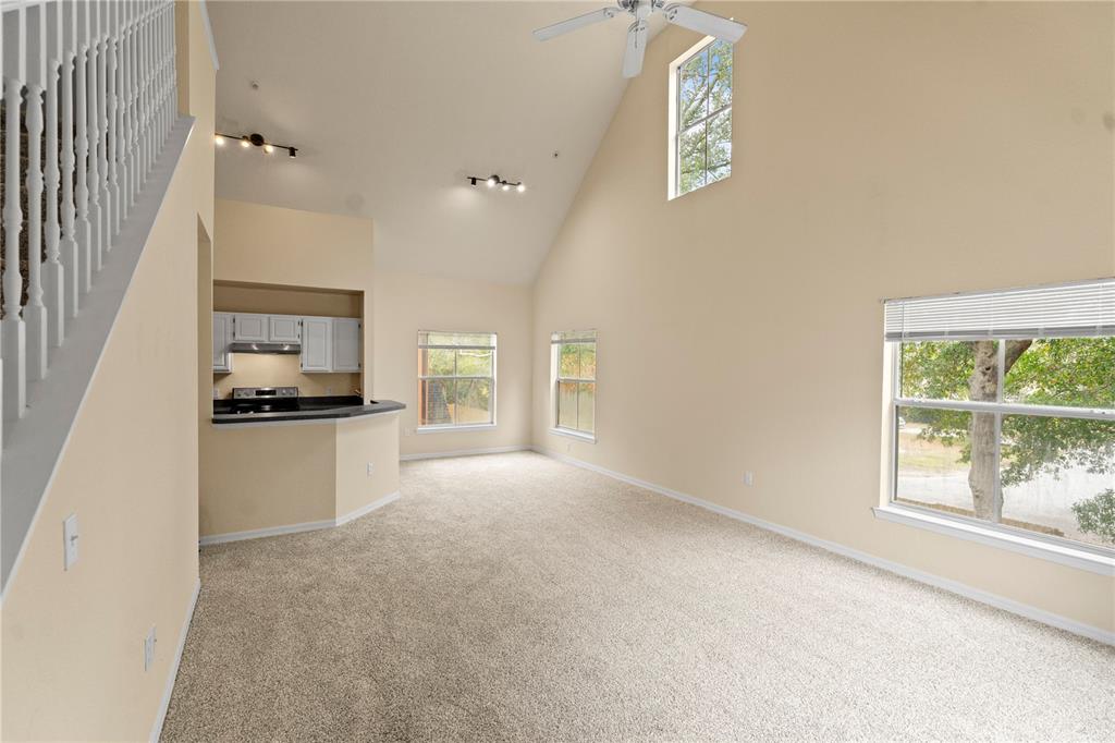 A carpeted living room features a vaulted ceiling, a ceiling fan, and an adjacent kitchen — 6021 WESTGATE DRIVE UNIT 823, ORLANDO, FL