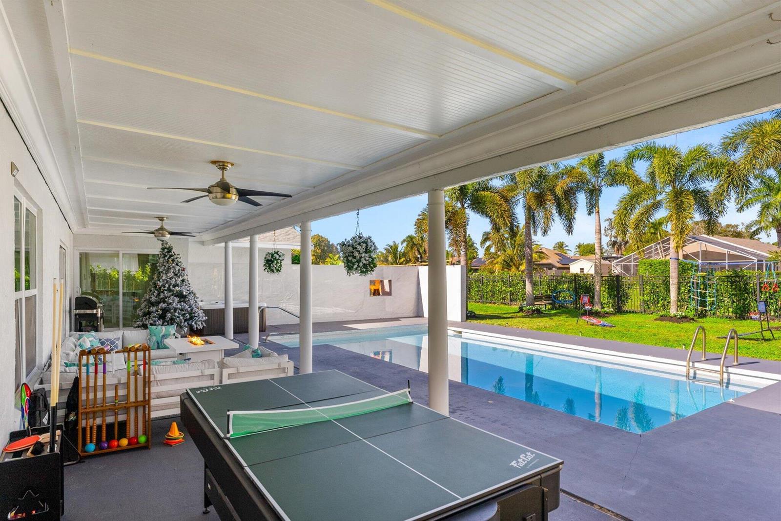A covered patio features a ping pong table, outdoor seating, and a swimming pool — 11647 Anhinga Drive, Wellington FL 33414, WELLINGTON, FL