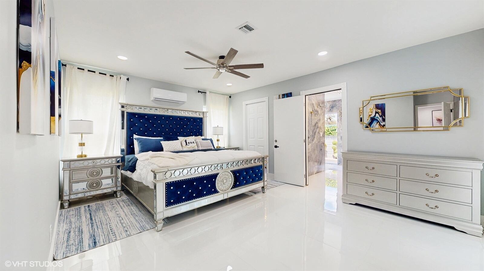 A bedroom features a blue tufted bed, mirrored furniture, and white tile flooring — 11647 Anhinga Drive, Wellington FL 33414, WELLINGTON, FL