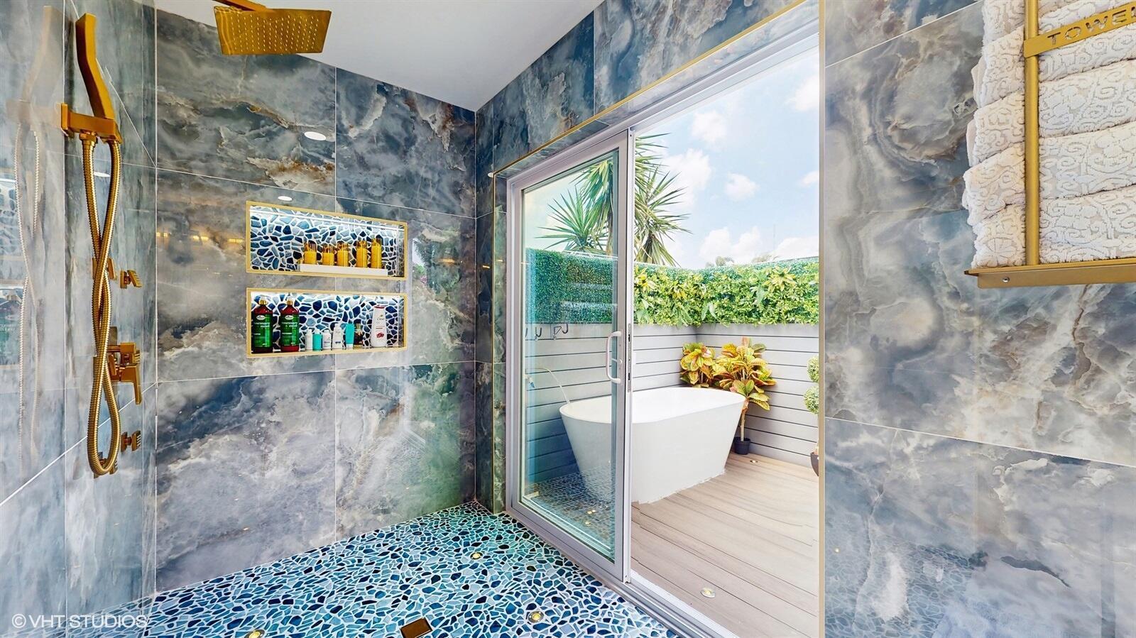 A shower with blue marble walls and pebble flooring opens to an outdoor soaking tub — 11647 Anhinga Drive, Wellington FL 33414, WELLINGTON, FL