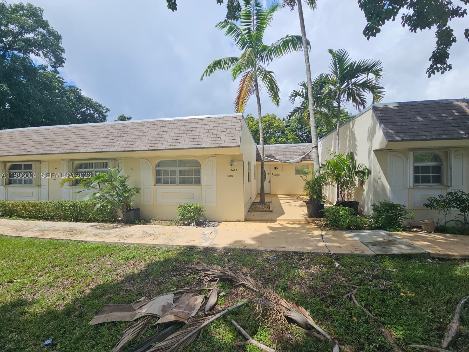 A single-story yellow house features a shingled roof, palm trees, and a paved walkway — 11287 SW 169th St # V41032, Miami FL 33157, MIAMI, FL