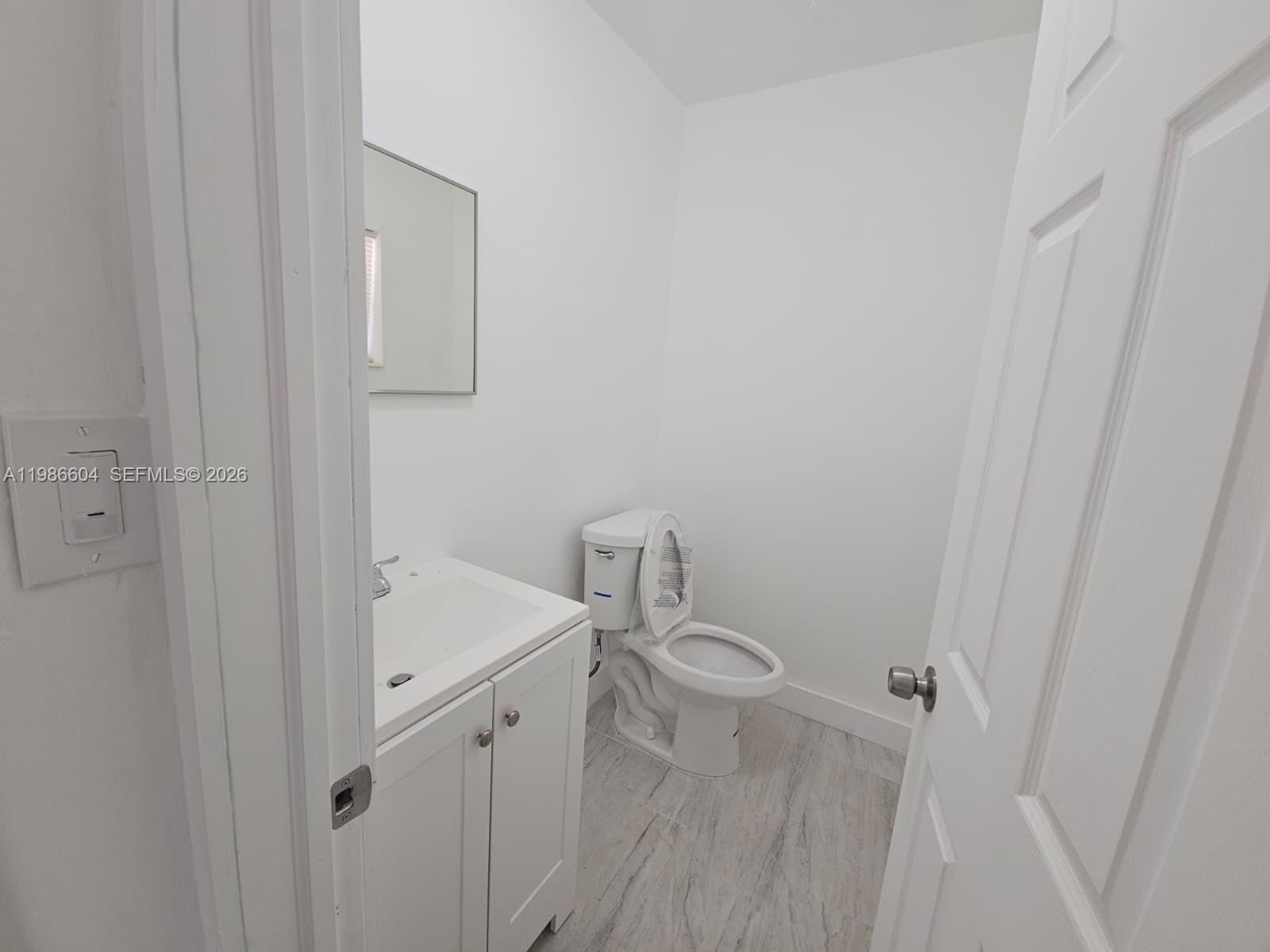 A small bathroom features a white vanity, a toilet, and light-colored wood-look tile flooring — 11287 SW 169th St # V41032, Miami FL 33157, MIAMI, FL