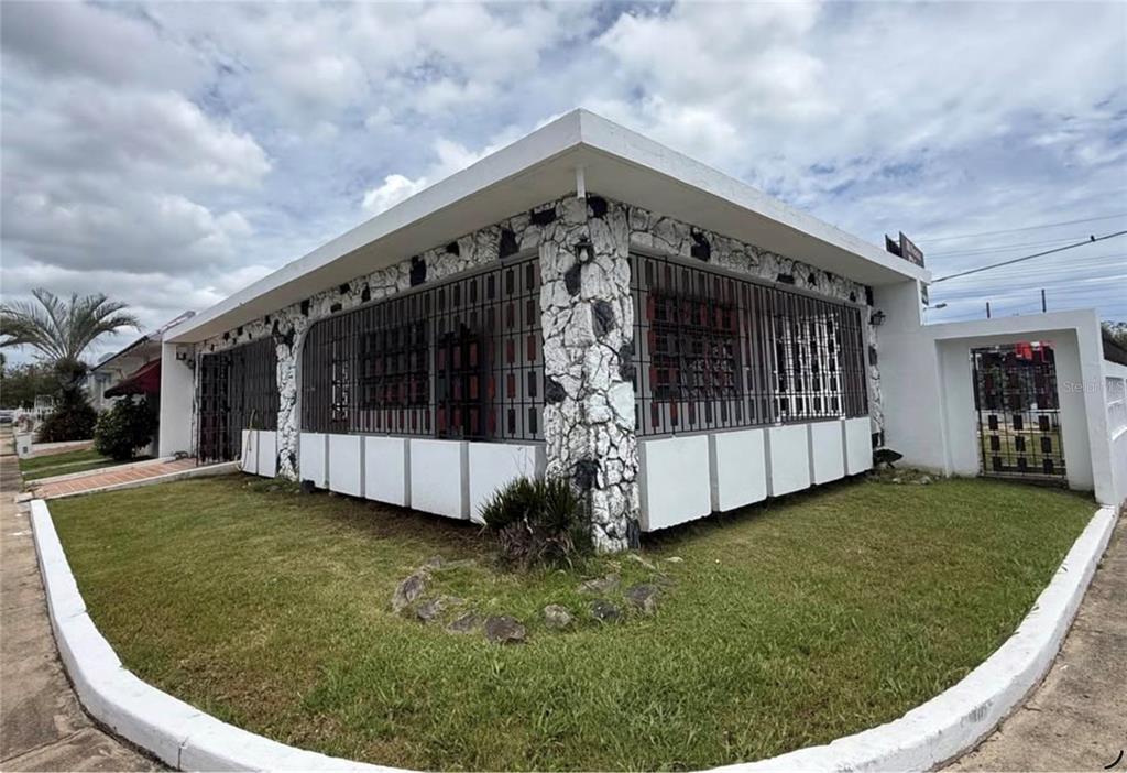 A single-story house with white stone corner pillars, security bars on windows, and a lawn — . ACACIA UNIT A37, CANOVANAS, PR