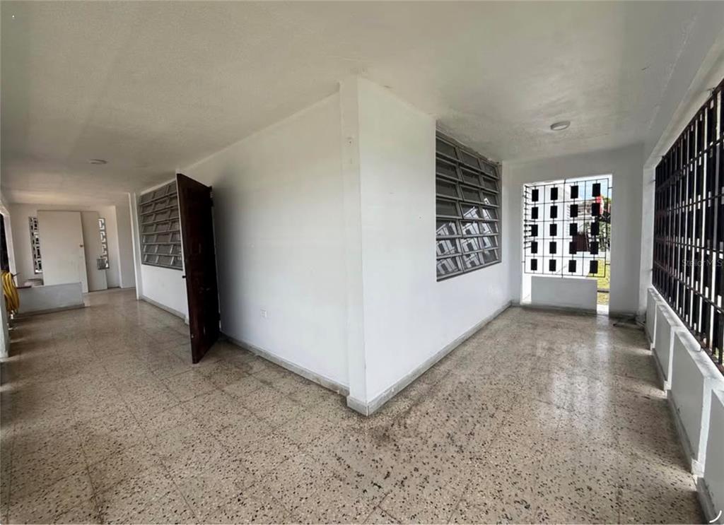 An open-air patio with a speckled tile floor, white walls, and metal security bars — . ACACIA UNIT A37, CANOVANAS, PR