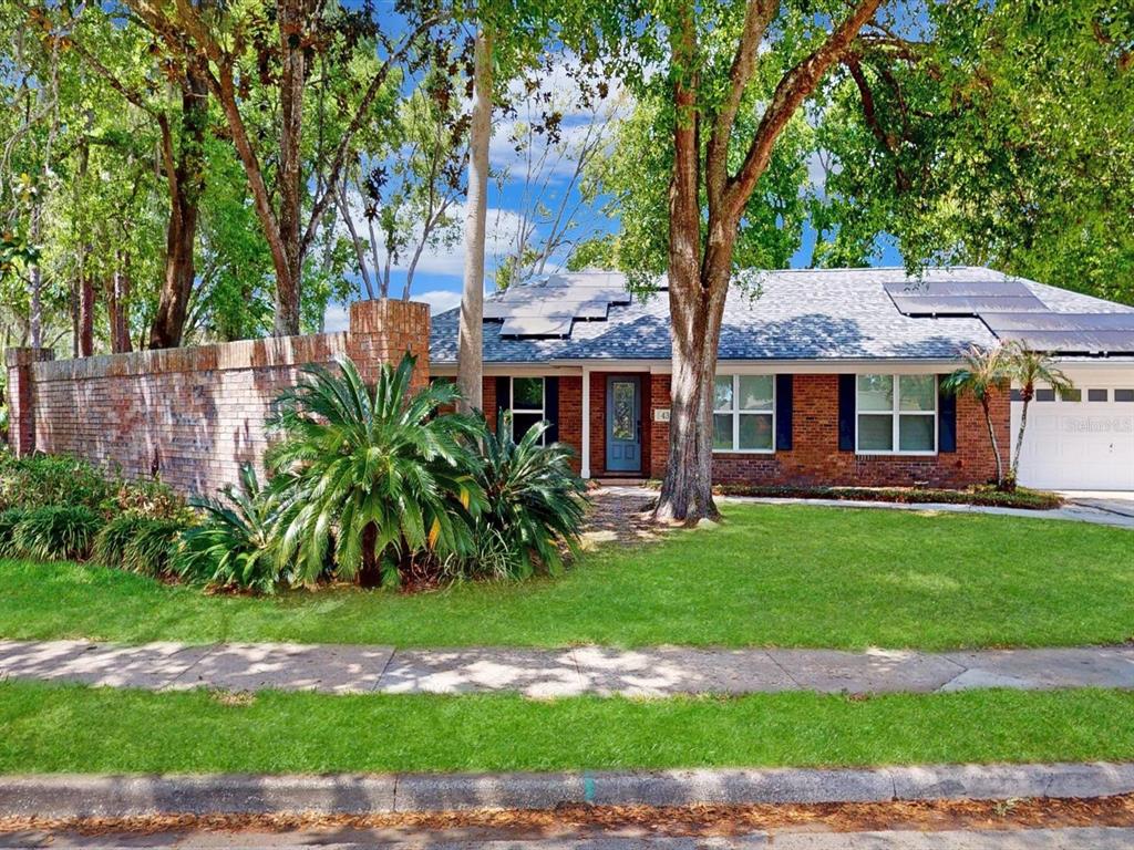A single-story brick house with a front lawn, solar panels, and a brick privacy wall — 432 WILDERNESS DRIVE, LONGWOOD, FL
