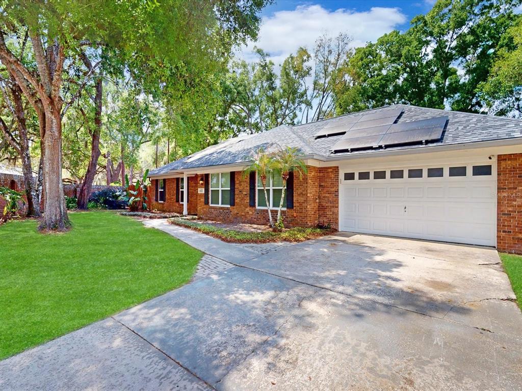 A single-story brick house with a two-car garage and solar panels on the roof — 432 WILDERNESS DRIVE, LONGWOOD, FL