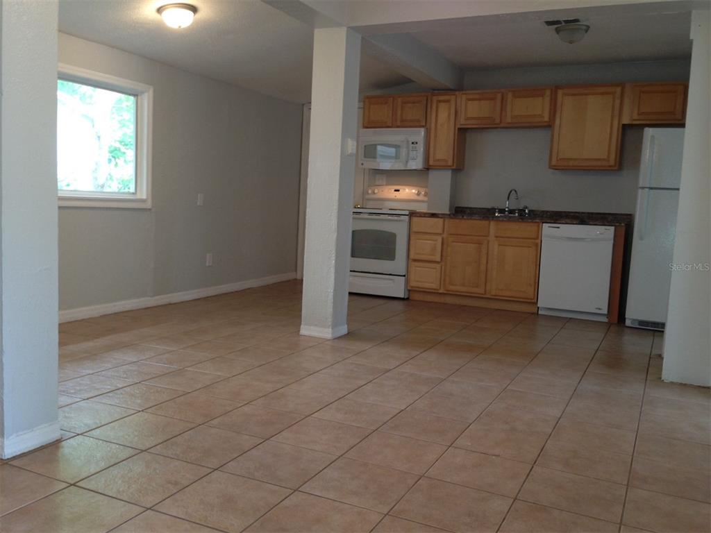 This kitchen features light-colored tile flooring, wooden cabinets, white appliances, and a central support pillar — 1328 CLOVERLAWN AVENUE UNIT B, ORLANDO, FL