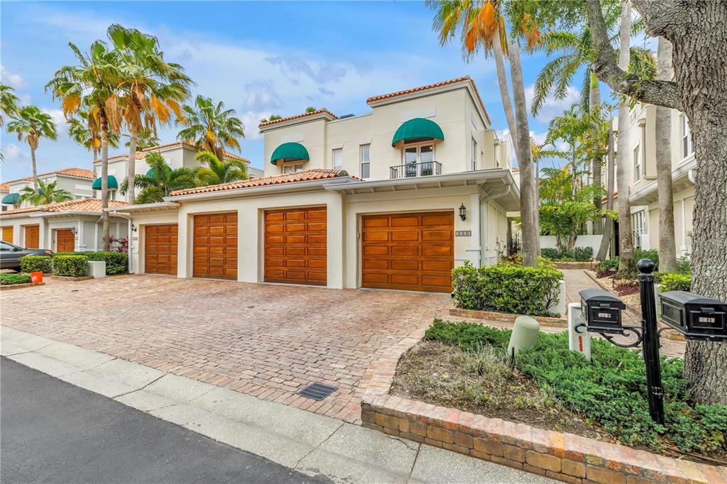 A multi-story house with four wooden garage doors and green awnings over the upper windows — 1133 ABBEYS WAY, TAMPA, FL