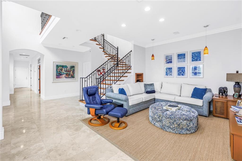 A living room features a curved staircase, tile flooring, a sectional sofa, and blue accents — 1133 ABBEYS WAY, TAMPA, FL
