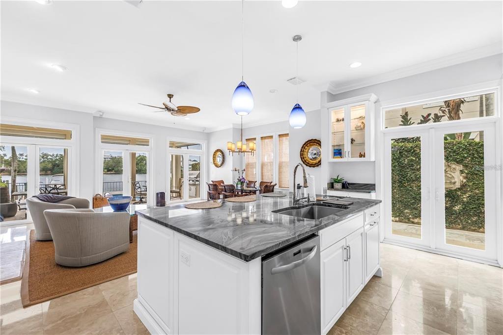 A kitchen island with a dark stone countertop sits in a bright, open-concept living space — 1133 ABBEYS WAY, TAMPA, FL