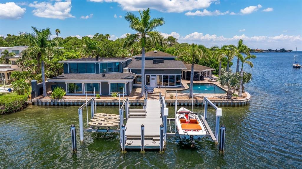 A waterfront house with a pool, a dock, and a boat lift on a sunny day — 2785 BAYSIDE DRIVE S, ST PETERSBURG, FL