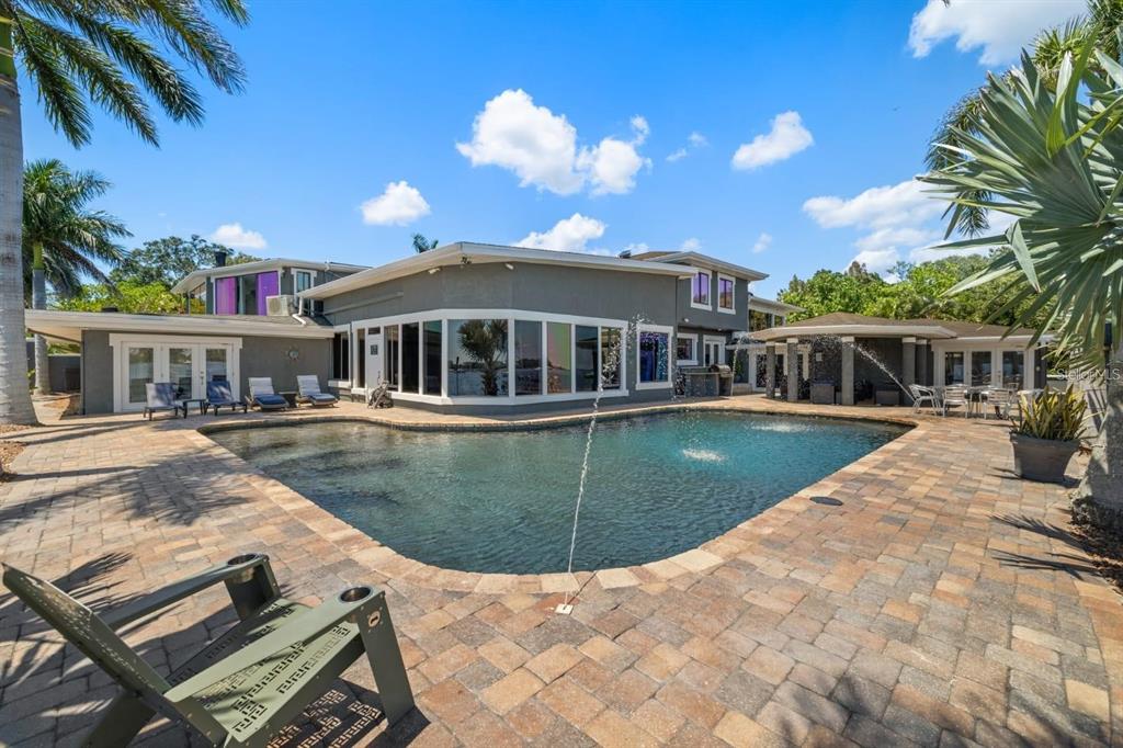 A gray two-story house features a swimming pool with a fountain on a paved patio — 2785 BAYSIDE DRIVE S, ST PETERSBURG, FL