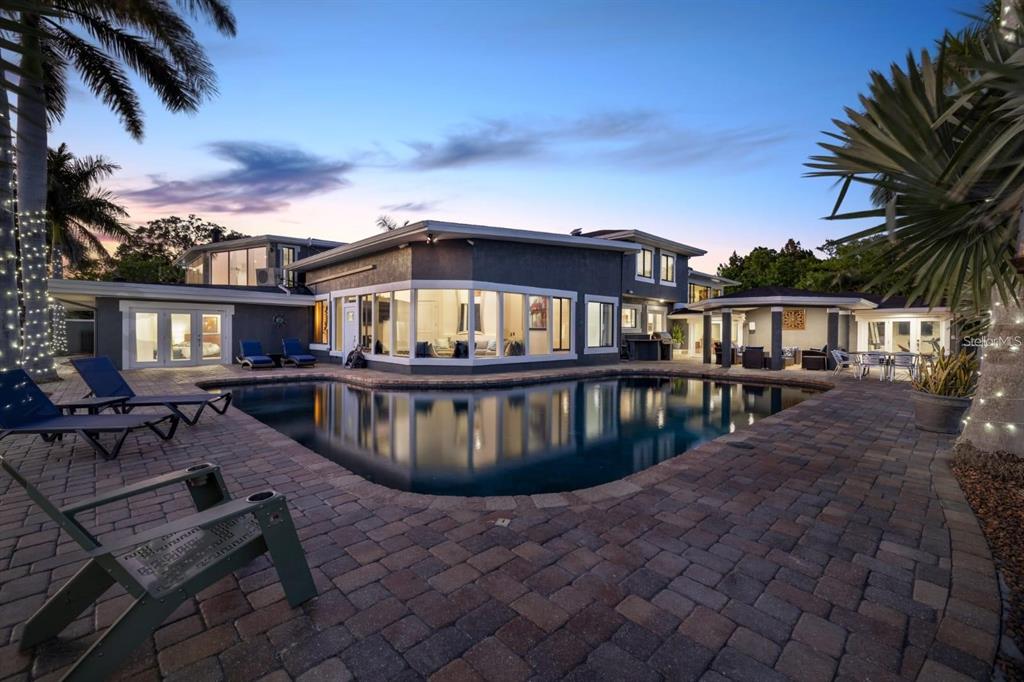 A multi-story house with a large swimming pool and brick patio at dusk — 2785 BAYSIDE DRIVE S, ST PETERSBURG, FL