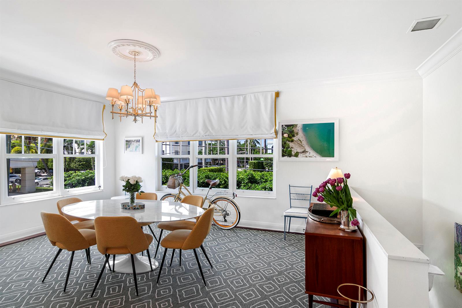 A dining room features a round marble table, mustard-colored chairs, and a patterned area rug — 311 Cocoanut Row # 2010, Palm Beach FL 33480, PALM BEACH, FL