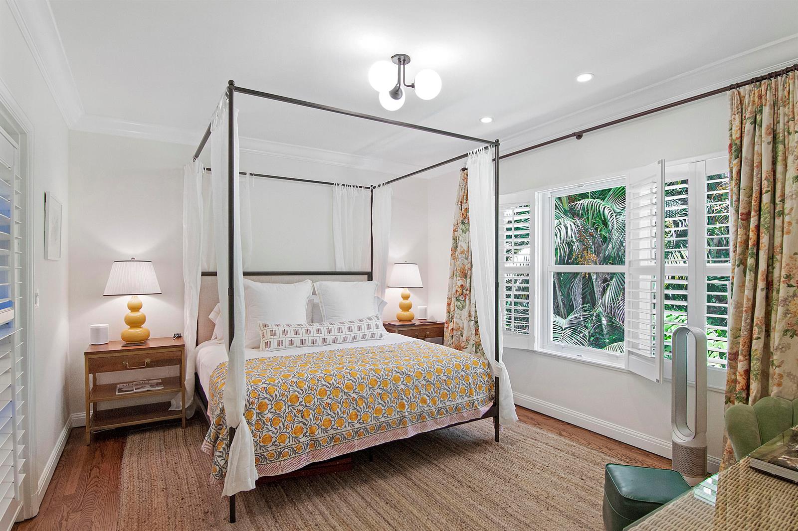 A bedroom features a four-poster bed, floral curtains, and a window overlooking lush tropical greenery — 311 Cocoanut Row # 2010, Palm Beach FL 33480, PALM BEACH, FL
