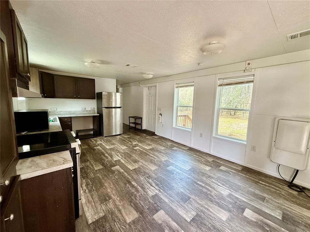 A kitchen and dining area with dark wood cabinets, stainless steel appliances, and wood-look flooring — 2716 FAST TROT TRAIL, LAKE WALES, FL