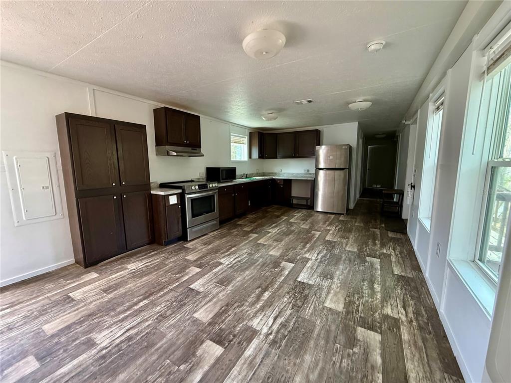 A kitchen features dark wood cabinets, stainless steel appliances, and wood-look flooring — 2716 FAST TROT TRAIL, LAKE WALES, FL