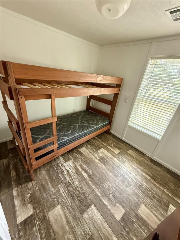 A bedroom features a wooden bunk bed, wood-look flooring, and a window with white blinds — 2716 FAST TROT TRAIL, LAKE WALES, FL