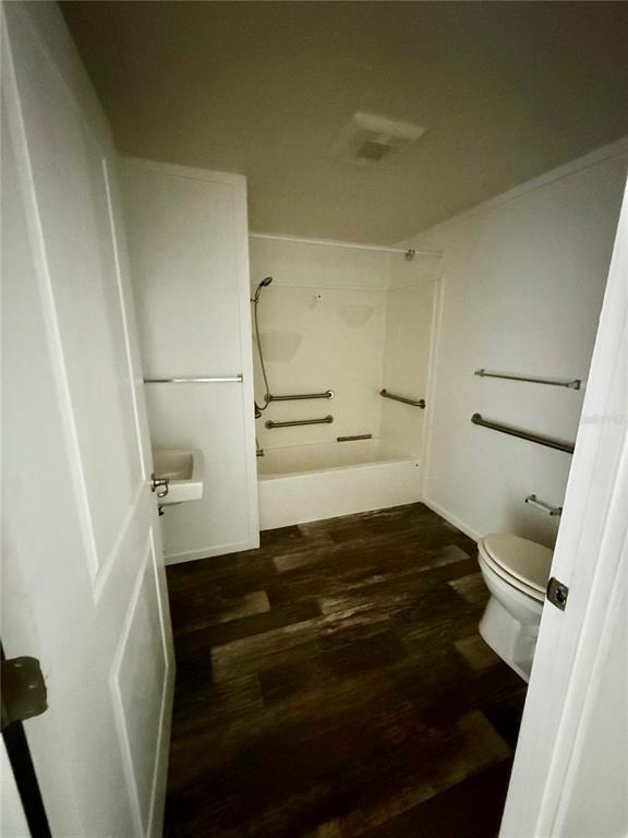 A bathroom features a white tub-shower combination, a toilet, a sink, and wood-look flooring — 2716 FAST TROT TRAIL, LAKE WALES, FL