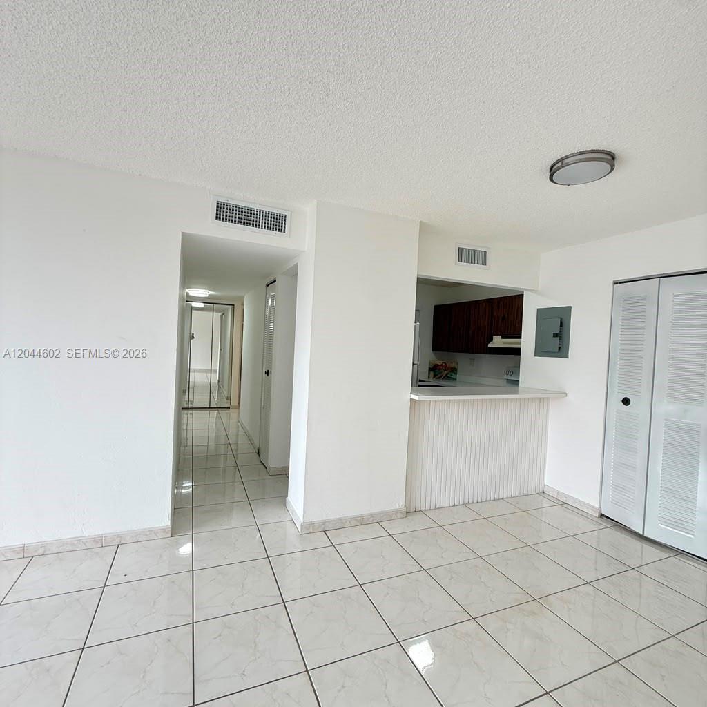 This interior view shows a tiled living area with a kitchen pass-through and hallway — MIAMI, FL
