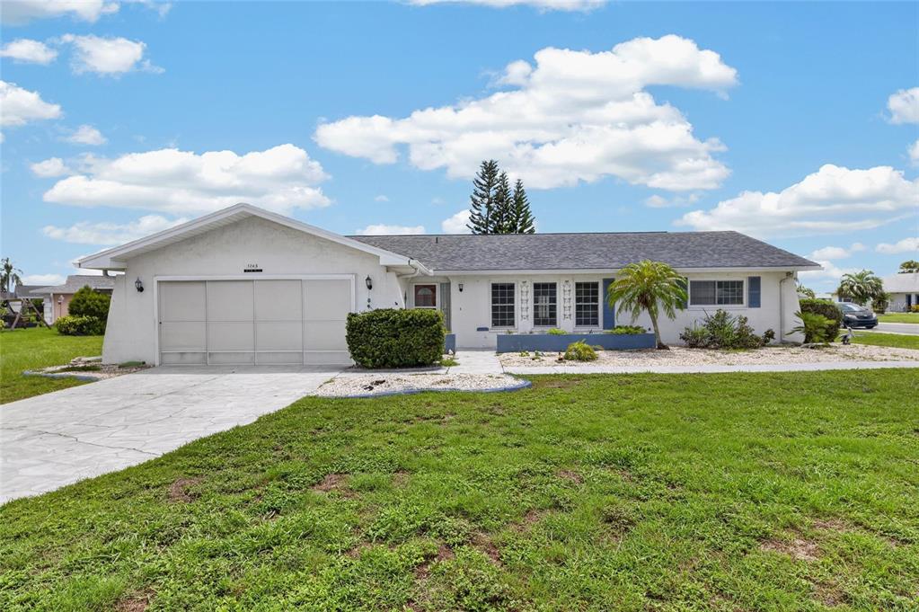 A single-story house with a white exterior, a two-car garage, and a front lawn — 1743 COCO PALM CIRCLE, SUN CITY CENTER, FL