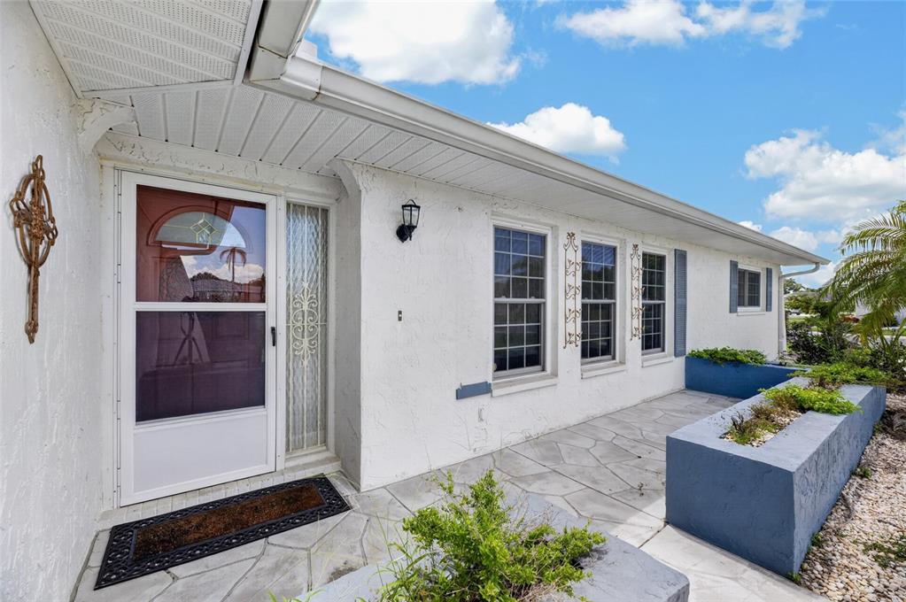 The exterior of a white house features a front porch with blue concrete planters — 1743 COCO PALM CIRCLE, SUN CITY CENTER, FL