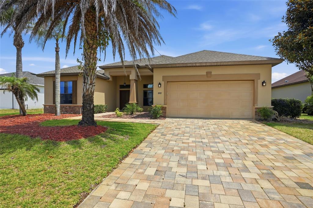 A single-story house with a tan stucco exterior, a paved driveway, and a palm tree — 8987 MISSISSIPPI RUN, WEEKI WACHEE, FL