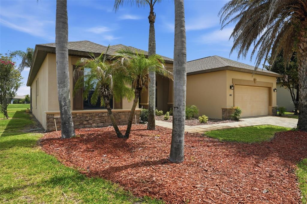 A single-story house with a tan stucco exterior, stone accents, and a two-car garage — 8987 MISSISSIPPI RUN, WEEKI WACHEE, FL