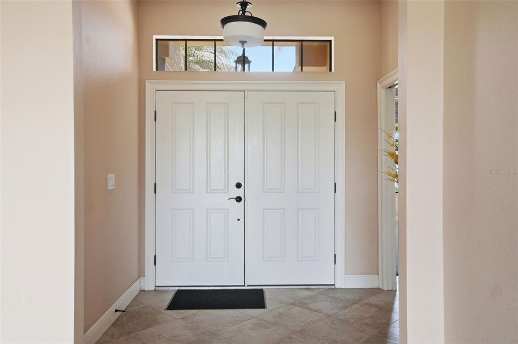 A tiled entryway features double white front doors with a transom window and pendant light — 8987 MISSISSIPPI RUN, WEEKI WACHEE, FL