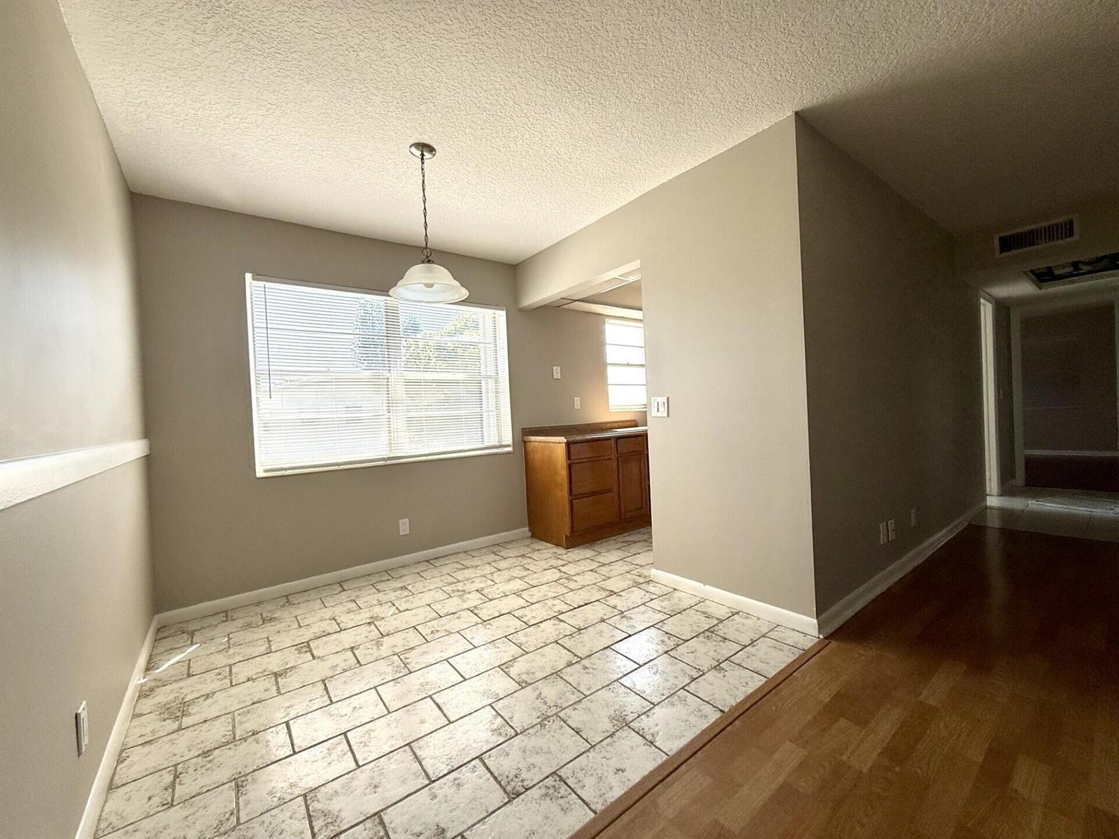 A dining area with tiled flooring, a pendant light, and an adjacent kitchen with cabinets — 93 Sheffield D # 93, West Palm Beach FL 33417, WEST PALM BEACH, FL
