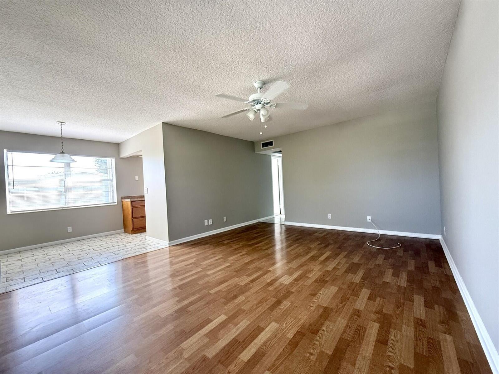 An open-concept living area features wood-look flooring, a ceiling fan, and an adjacent tiled dining space — 93 Sheffield D # 93, West Palm Beach FL 33417, WEST PALM BEACH, FL