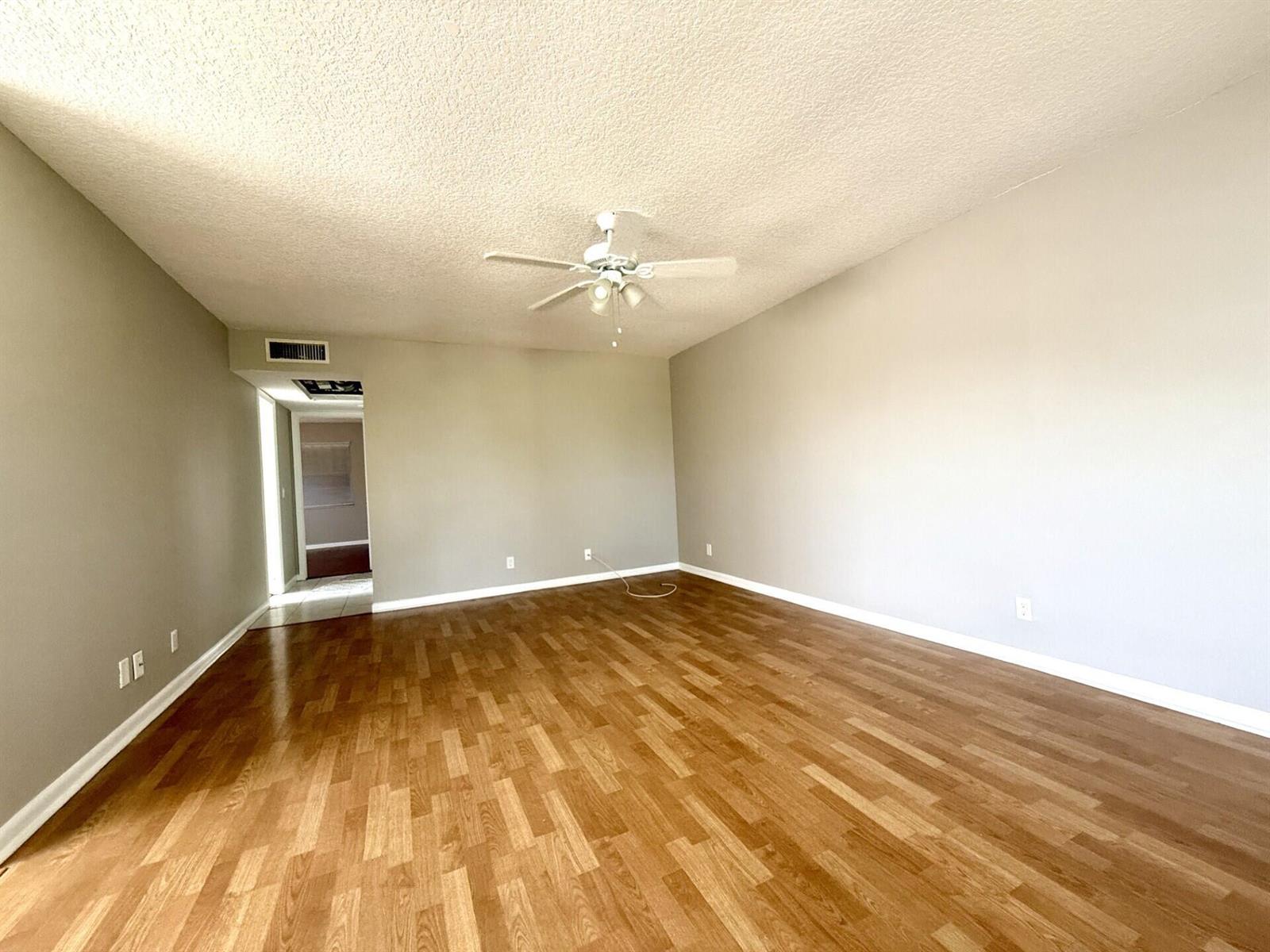 An empty room features light gray walls, wood-look flooring, and a white ceiling fan — 93 Sheffield D # 93, West Palm Beach FL 33417, WEST PALM BEACH, FL