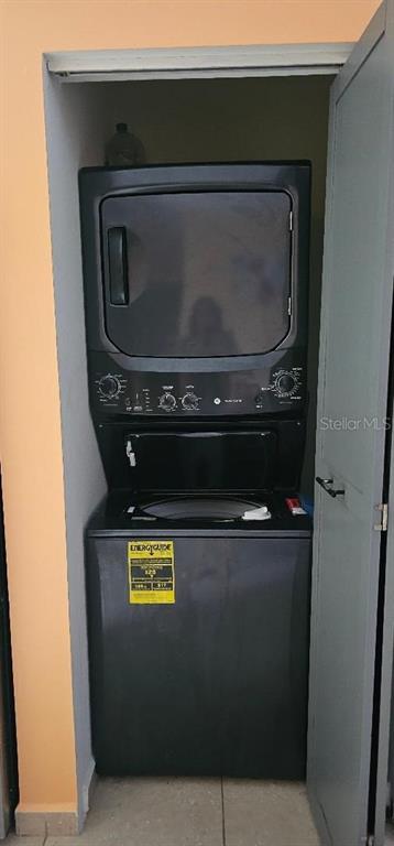 A black stacked washer and dryer unit is installed inside a small closet — Apt A-2 Ponciana Condo CARR 413 KM.4.1, RINCON, PR