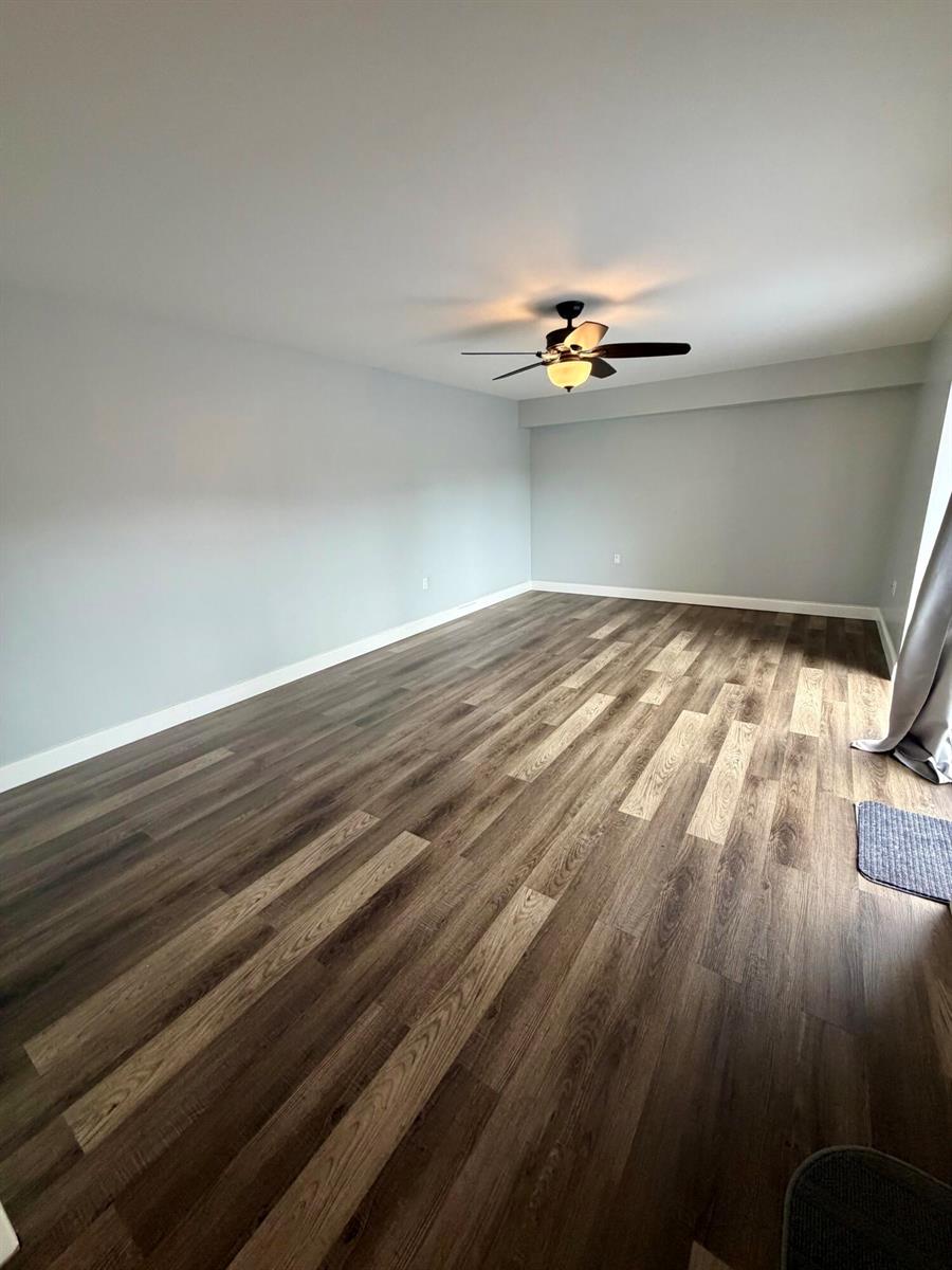 An empty room features light gray walls, wood-look plank flooring, and a ceiling fan — 1611 16th Way, West Palm Beach FL 33407, WEST PALM BEACH, FL