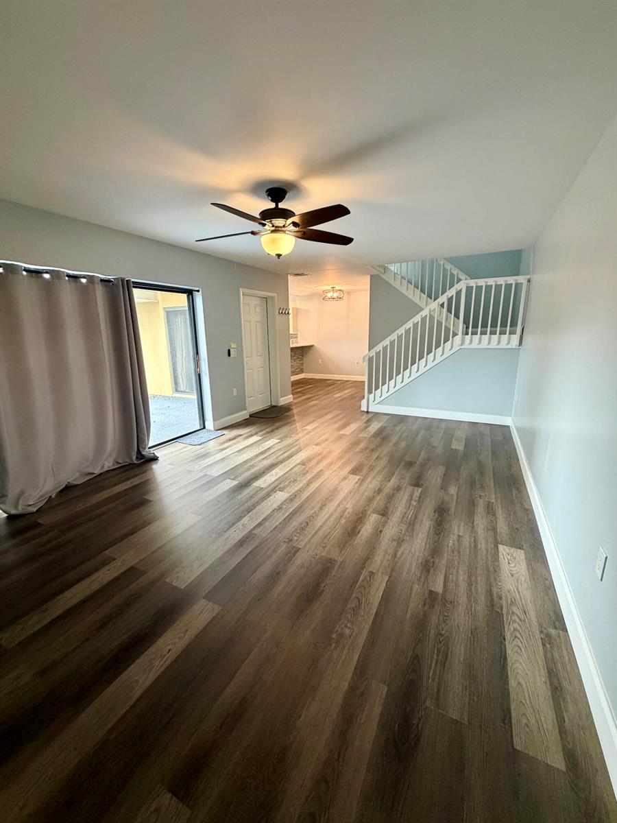 A living room with wood-look flooring, a ceiling fan, a sliding glass door, and stairs — 1611 16th Way, West Palm Beach FL 33407, WEST PALM BEACH, FL