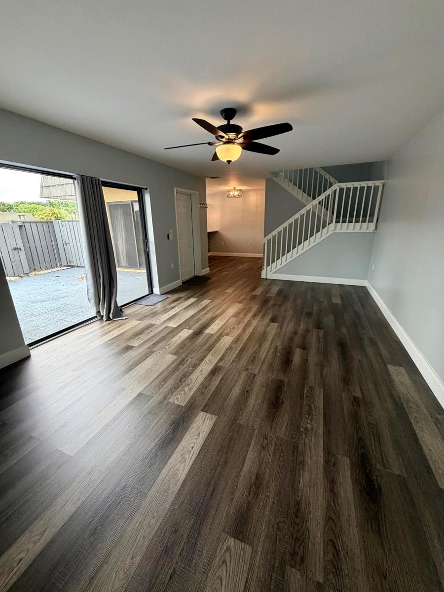 An open living area features wood-look flooring, a ceiling fan, a staircase, and sliding doors — 1611 16th Way, West Palm Beach FL 33407, WEST PALM BEACH, FL