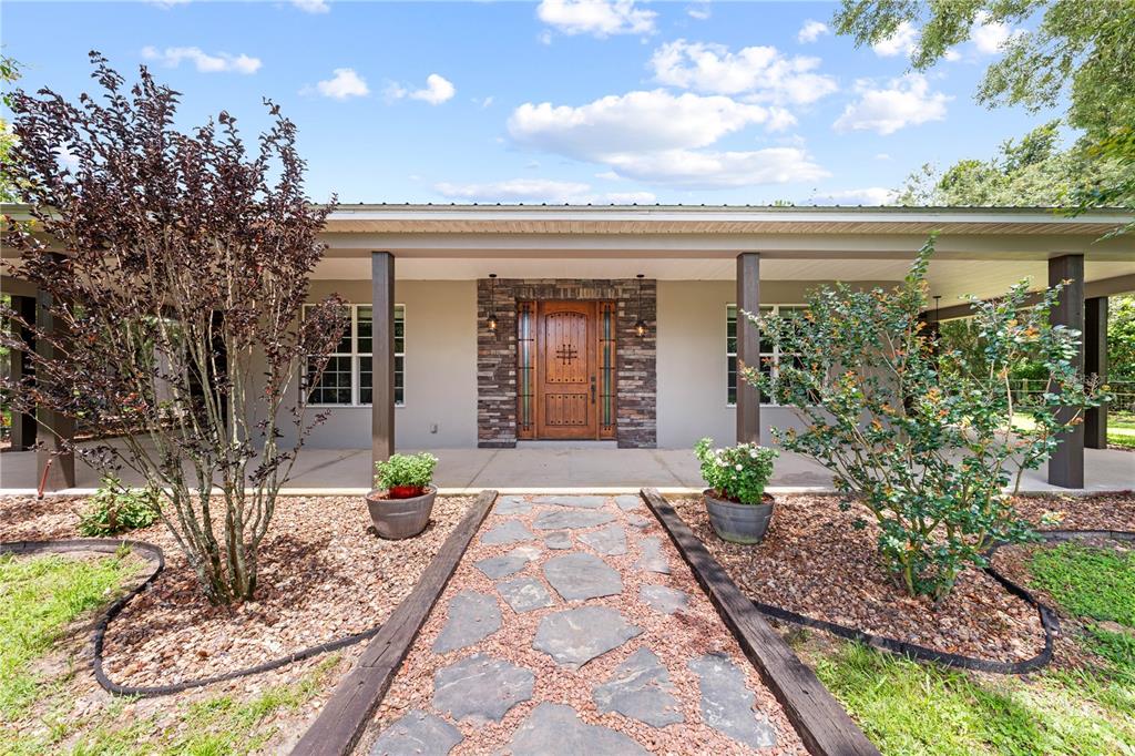 A stone walkway leads to the front entrance of a house with a covered porch — 4295 RAMBLER AVE, ST CLOUD, FL