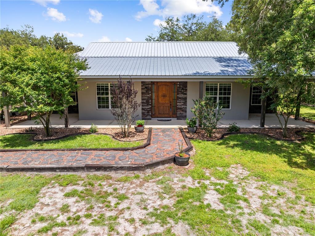 A single-story house with a metal roof, stone entryway, and a stone walkway — 4295 RAMBLER AVE, ST CLOUD, FL