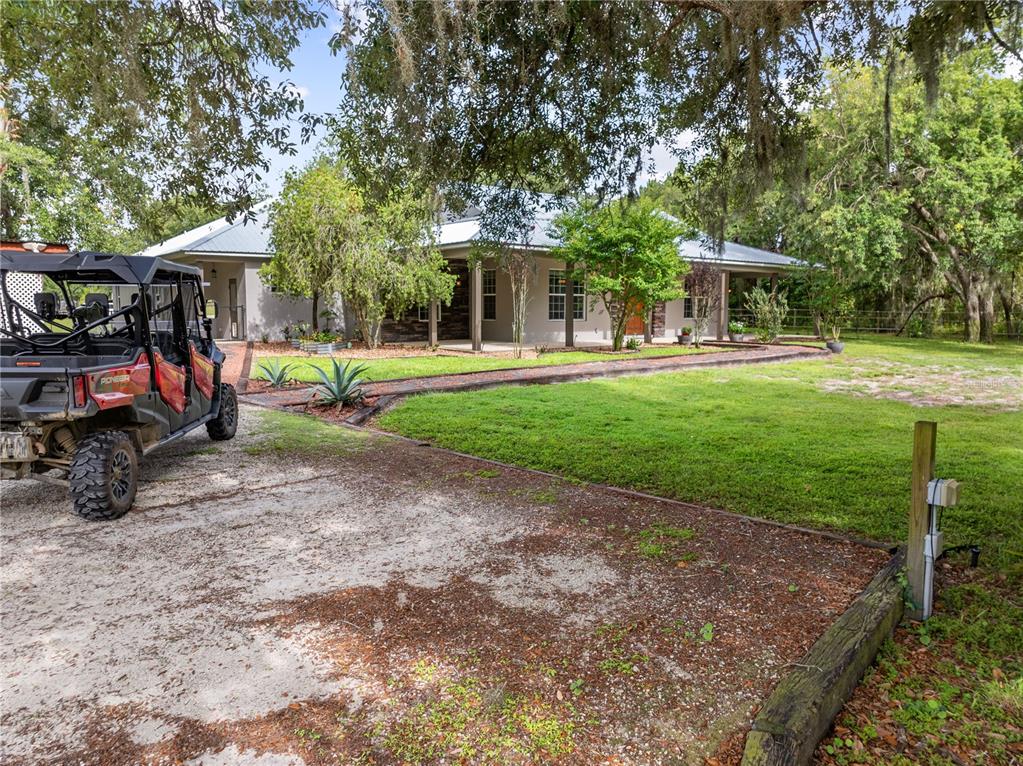 A side view of a single-story house with a metal roof and a parked UTV — 4295 RAMBLER AVE, ST CLOUD, FL