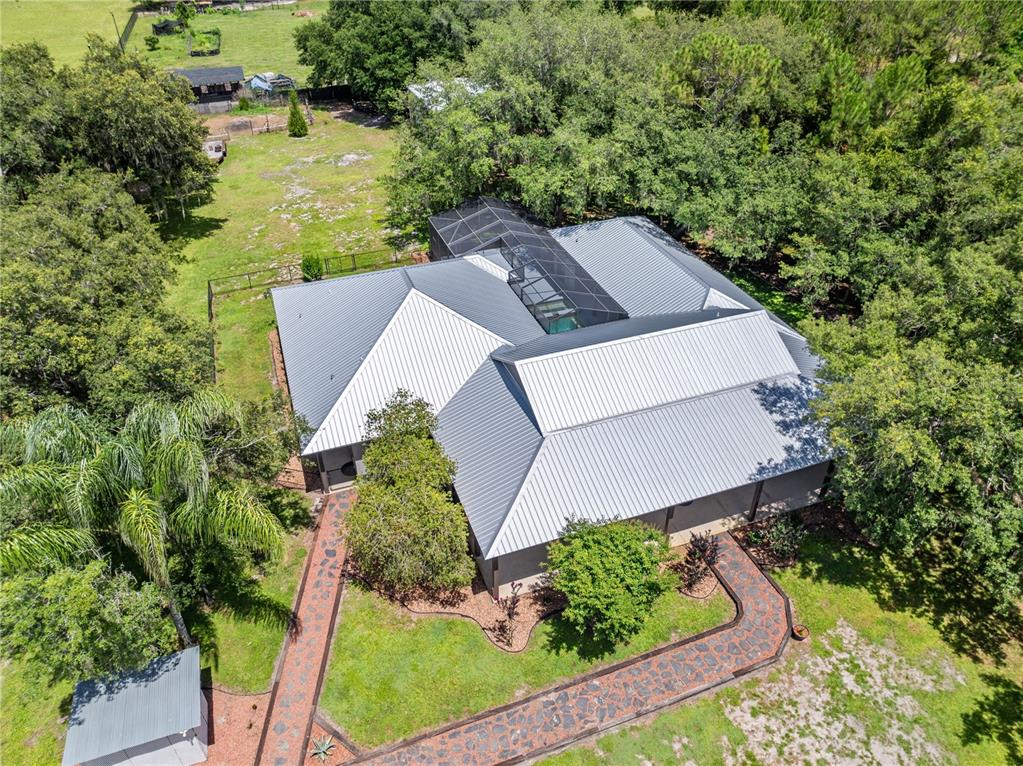 An aerial view shows a house with a metal roof and a screened-in pool area — 4295 RAMBLER AVE, ST CLOUD, FL